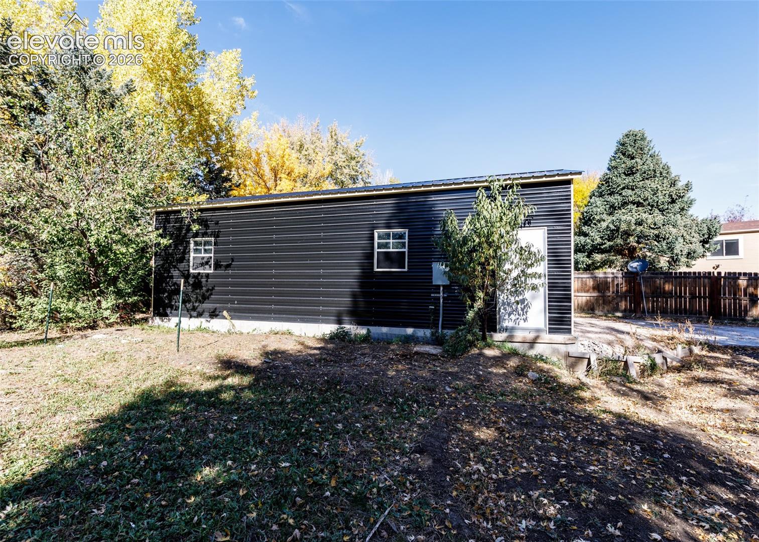 Detached structure featuring black corrugated metal siding, a single entry door, and two rectangular windows