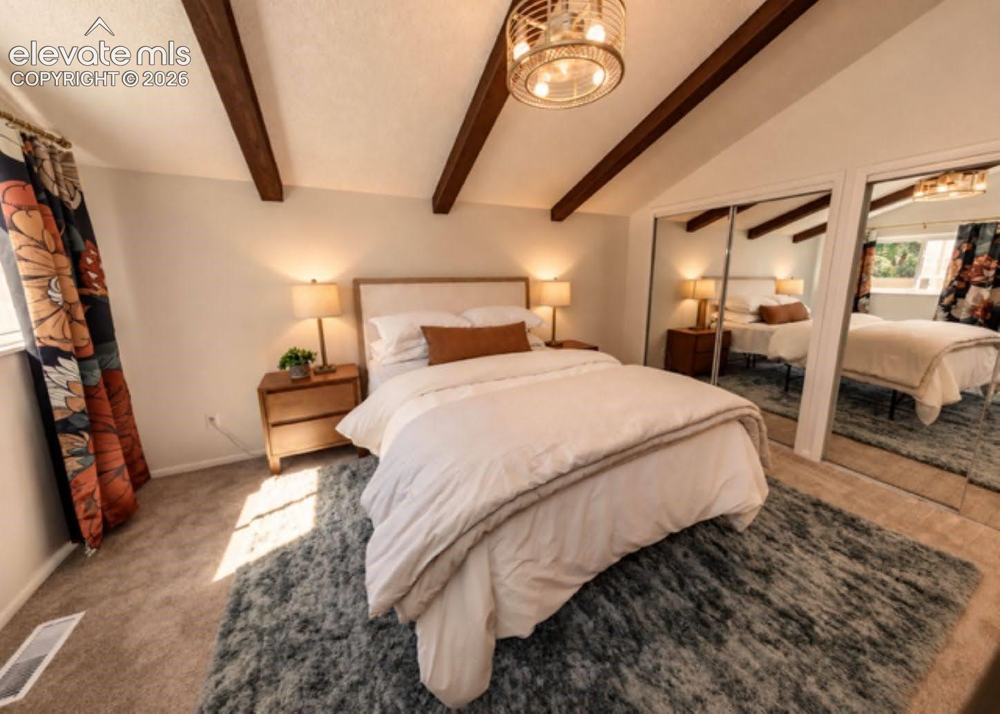 Vaulted ceiling with exposed wood beams, circular woven-finish light fixture, and mirrored sliding closet doors