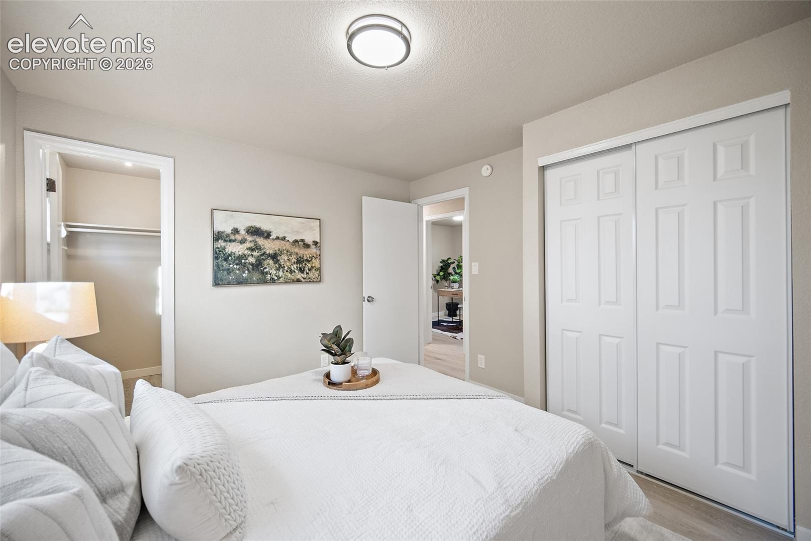Bedroom featuring light-toned walls, white trim, a built-in closet with bi-fold doors, and a ceiling-mounted light fixture