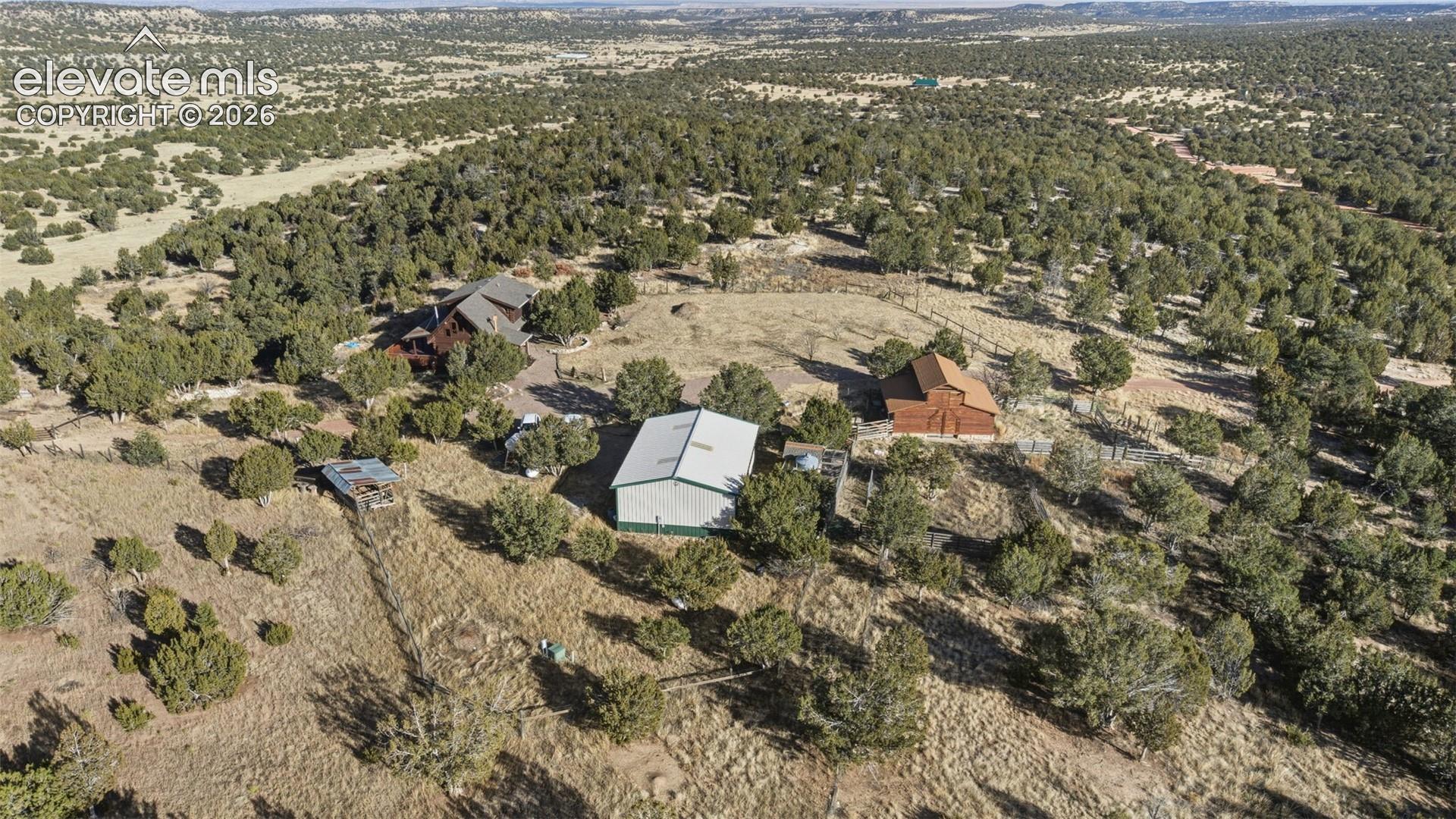 Expansive property featuring a main residence, a barn, a large outbuilding, and mature trees
