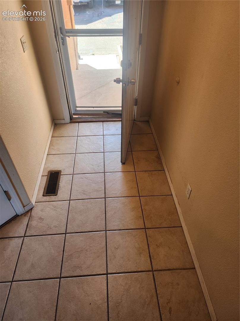 Tiled entryway with a storm door, interior door, and light-colored walls