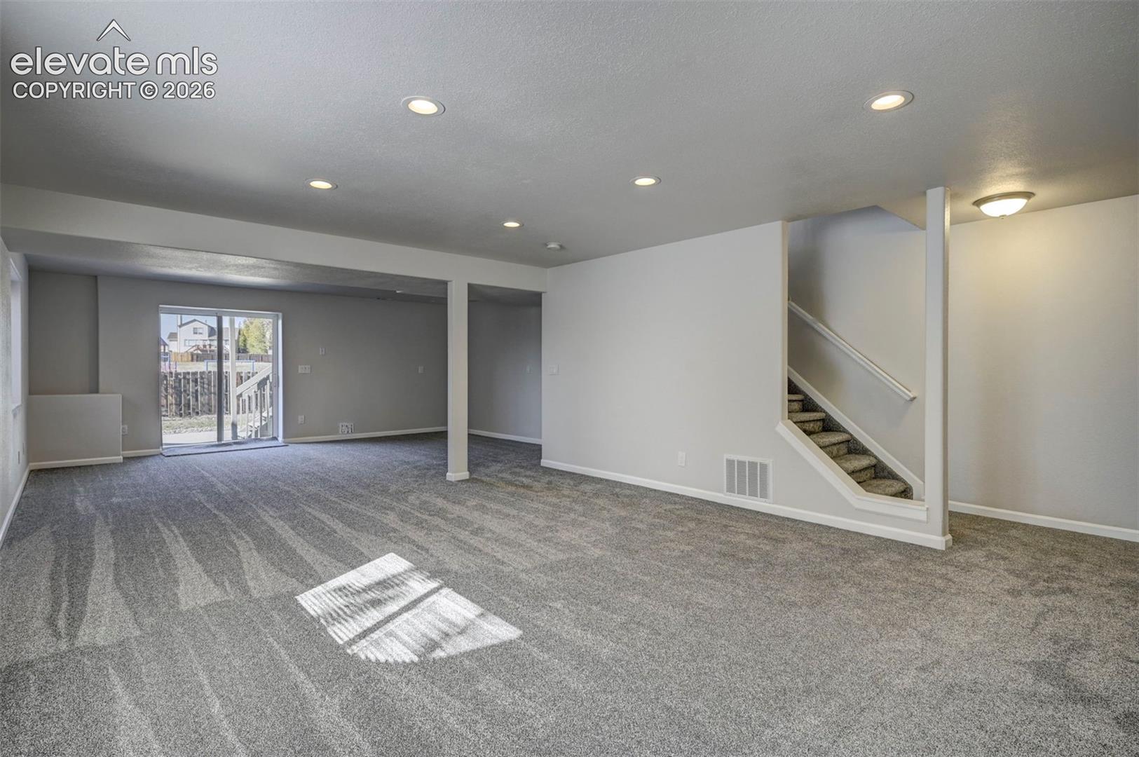 Open-concept interior featuring neutral wall tones, recessed lighting, wall-to-wall carpeting, and sliding glass doors with exterior access