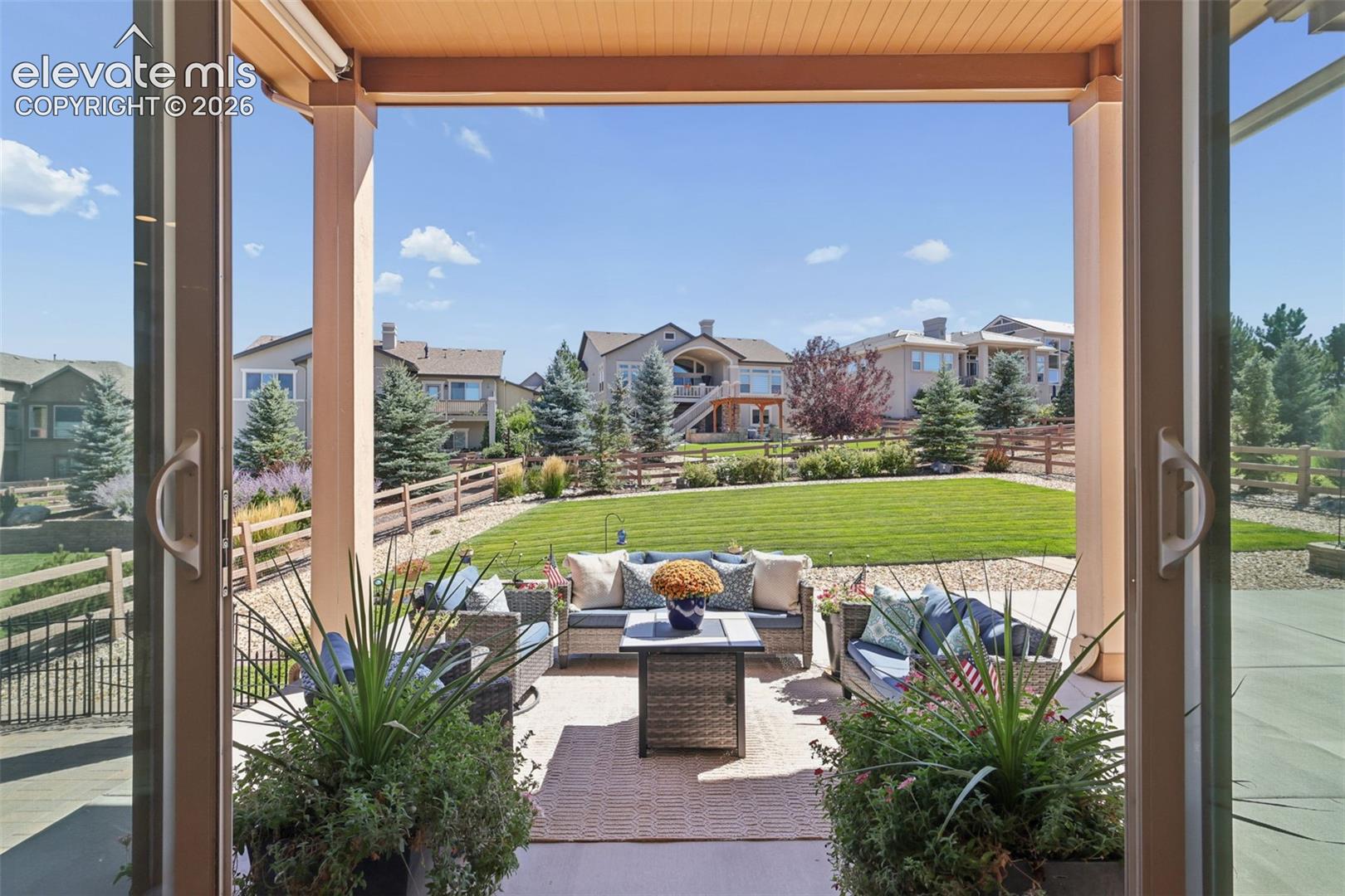 Expansive covered patio with a textured ceiling, opening to a large, irrigated lawn