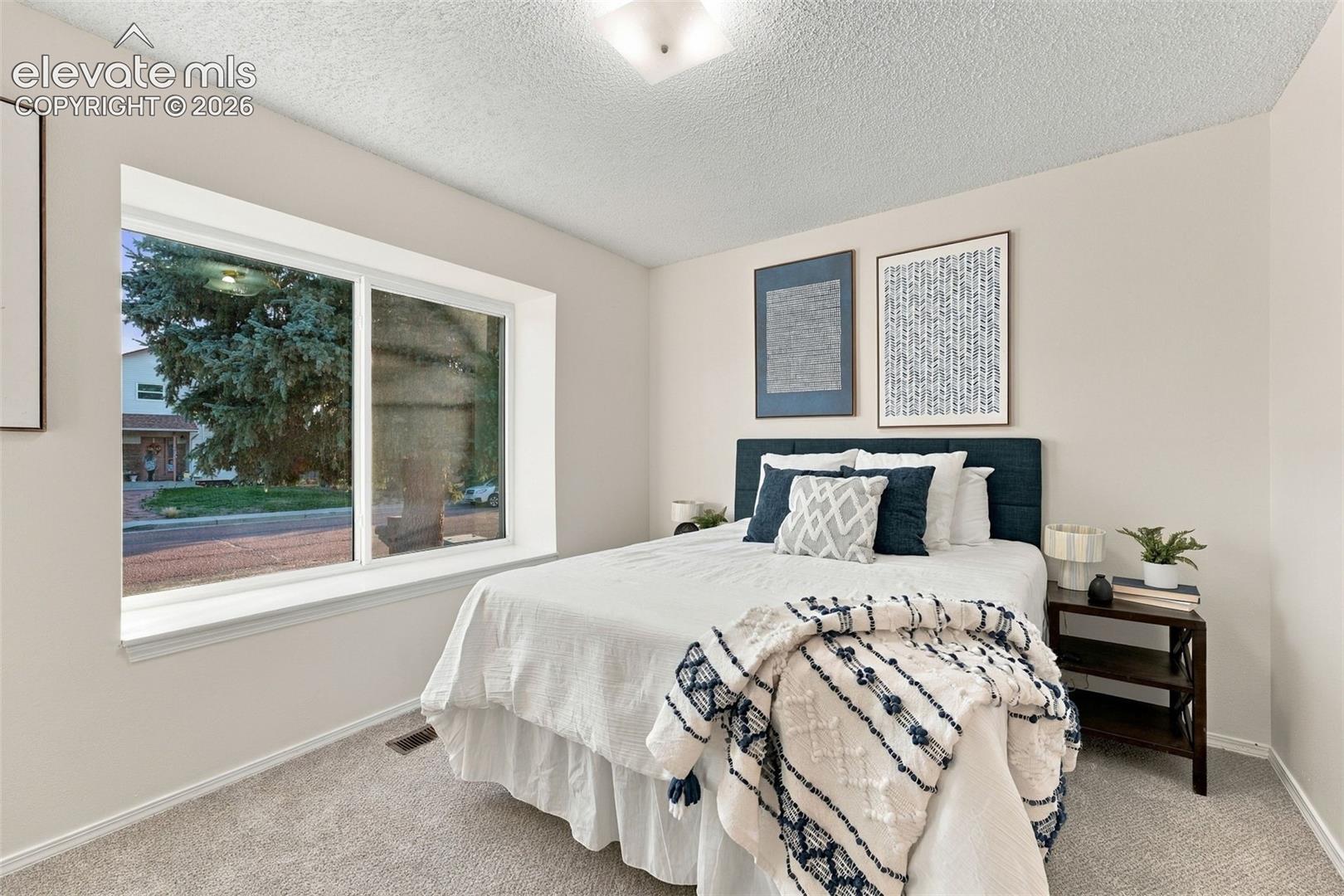 Large picture window providing natural light, neutral wall paint, and textured ceiling finish