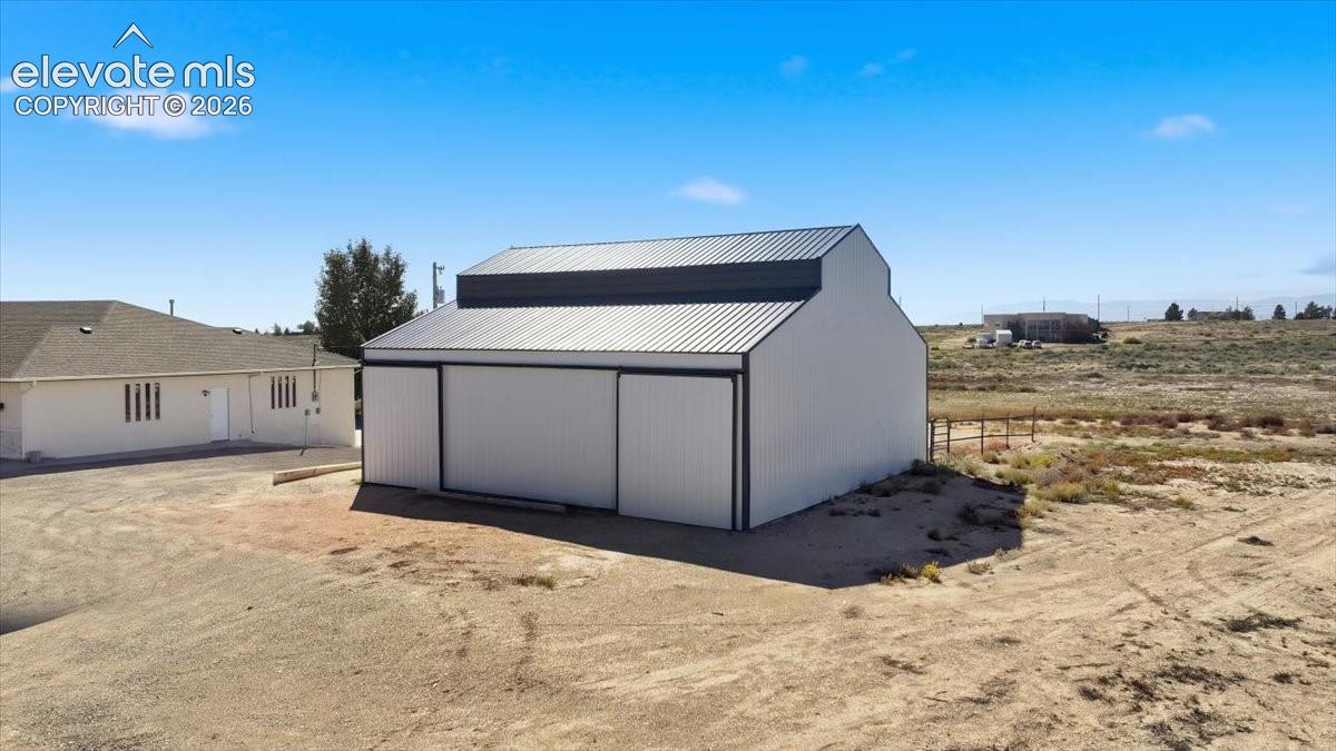 Detached barn structure featuring metal vertical-panel siding, a gambrel roofline, and sliding entry doors