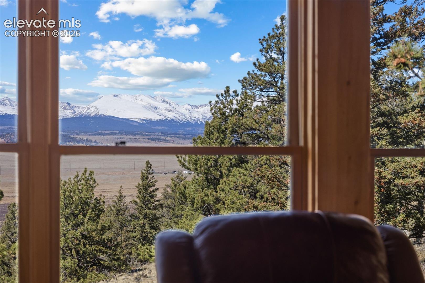 Large wood-framed windows overlooking expansive mountain and forest scenery