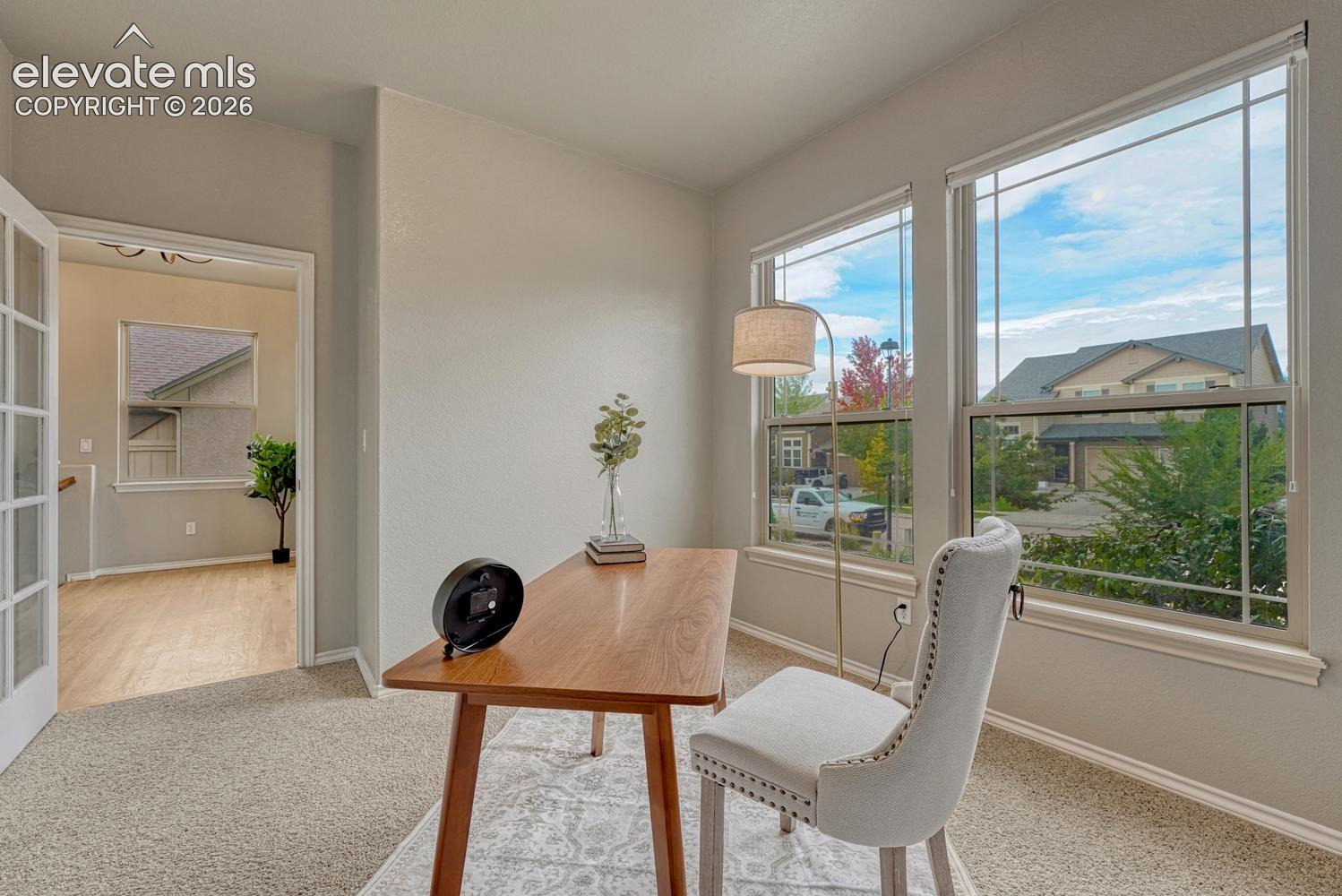 French doors lead into the front office with neutral carpet and front yard views.