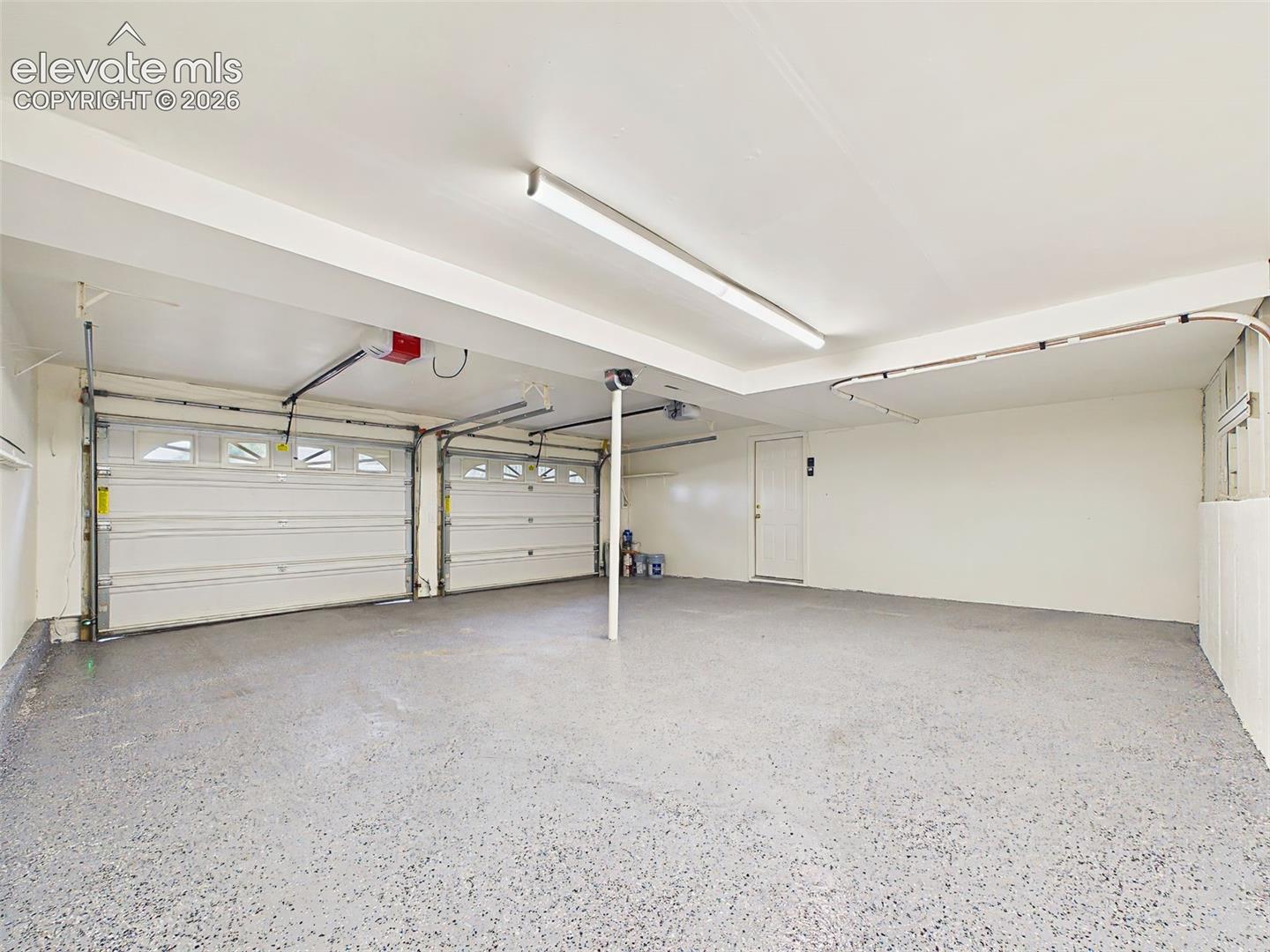 Another view highlights the expansive layout, dual garage doors with automatic openers, and convenient interior access.
