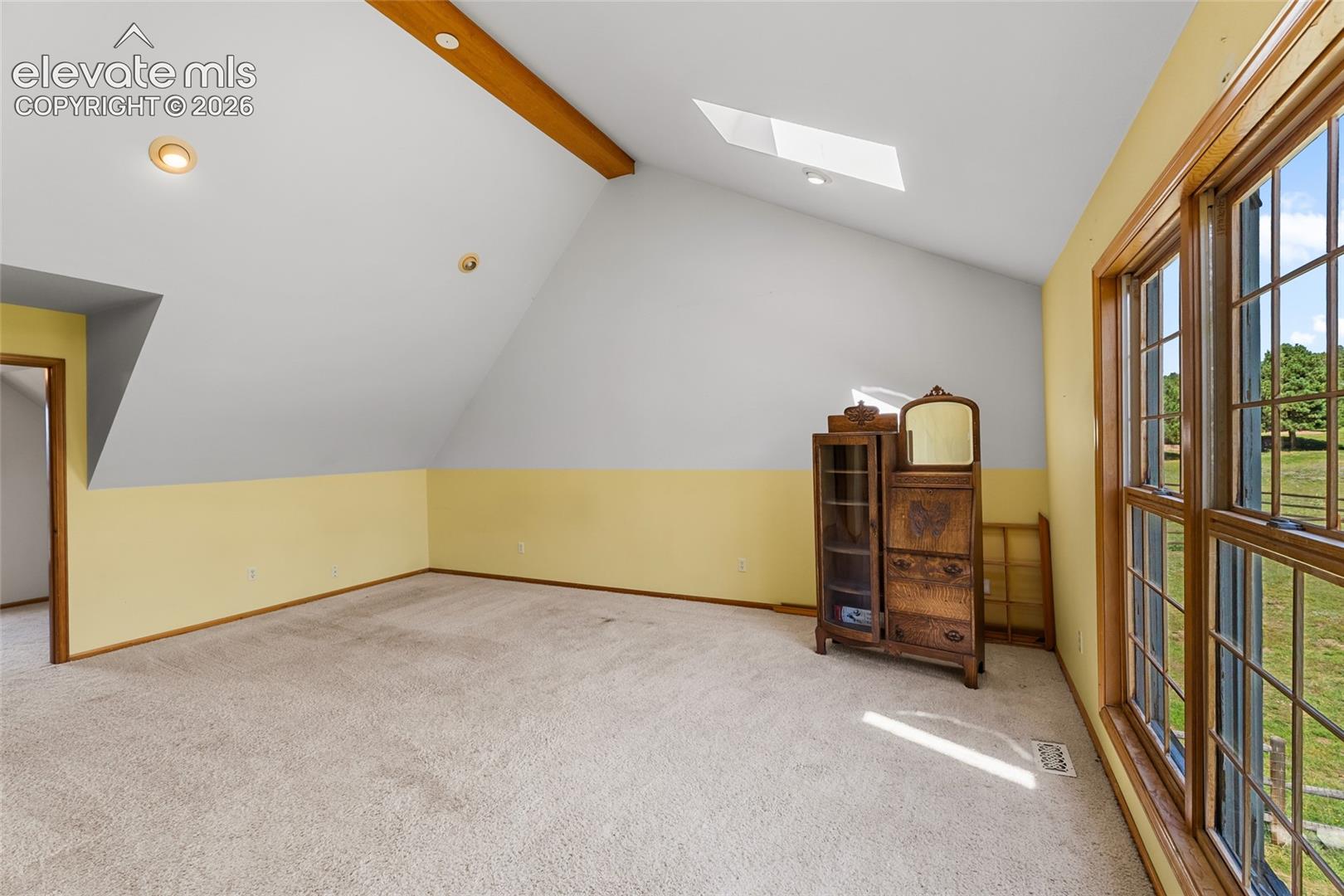 Sloped ceiling with an exposed wood beam, recessed lighting, and a skylight