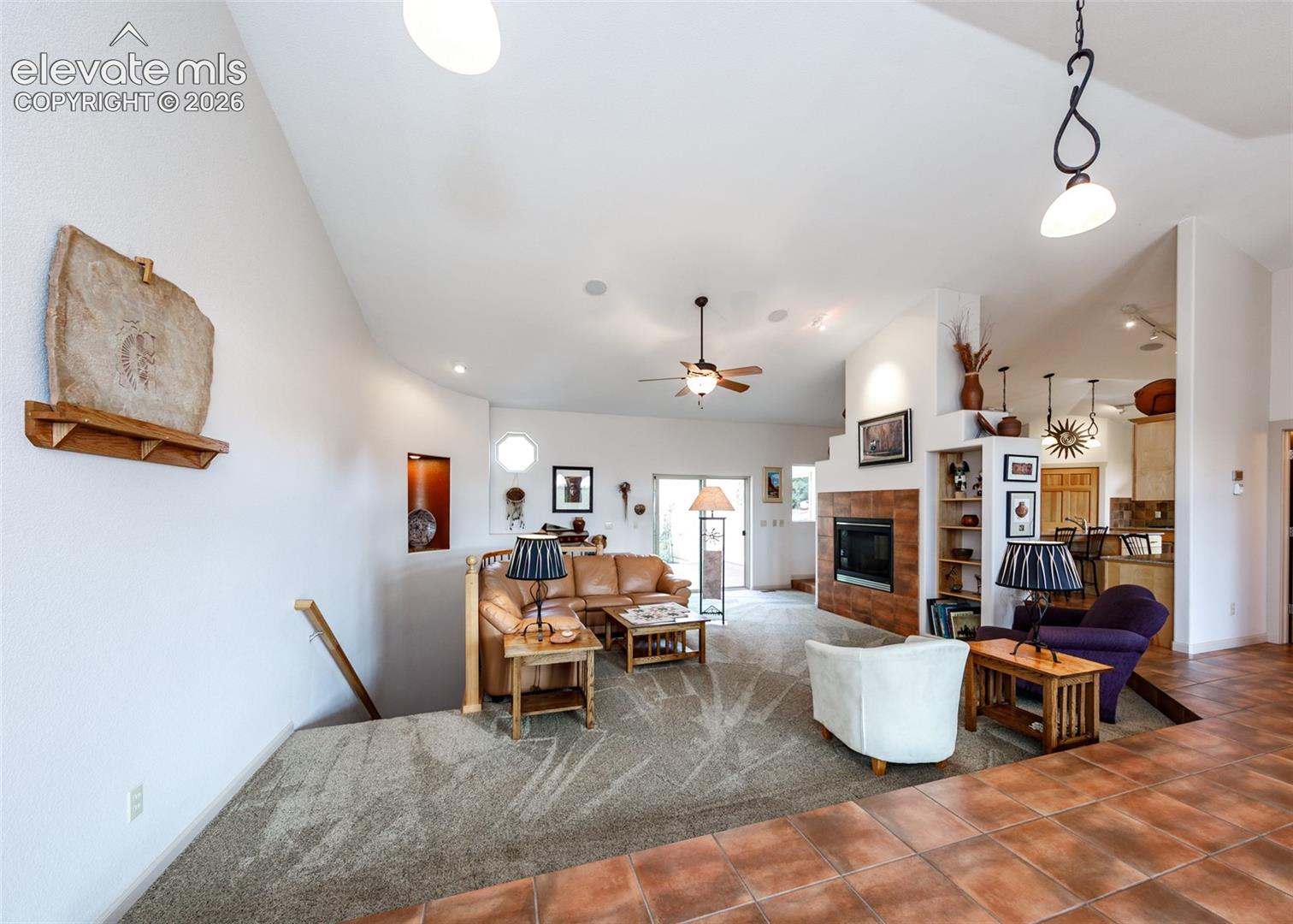 Open-concept living area featuring soaring vaulted ceilings, step down, and extensive main level title flooring.
