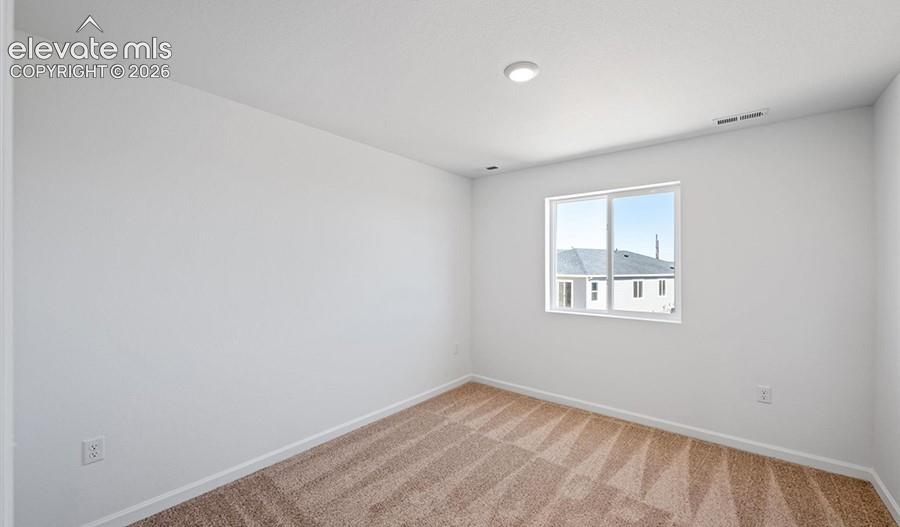 Neutral interior room featuring neutral-tone carpeting, smooth white walls, and a single-pane sliding window