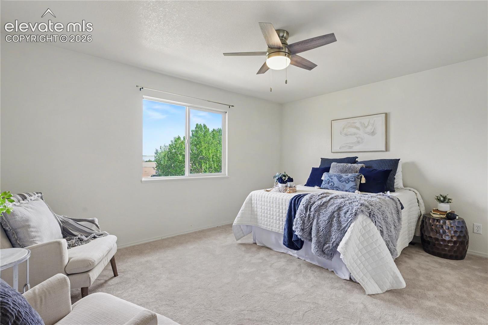 Bedroom featuring a ceiling fan with integrated lighting, a double-pane window, neutral carpet flooring, and light-colored walls