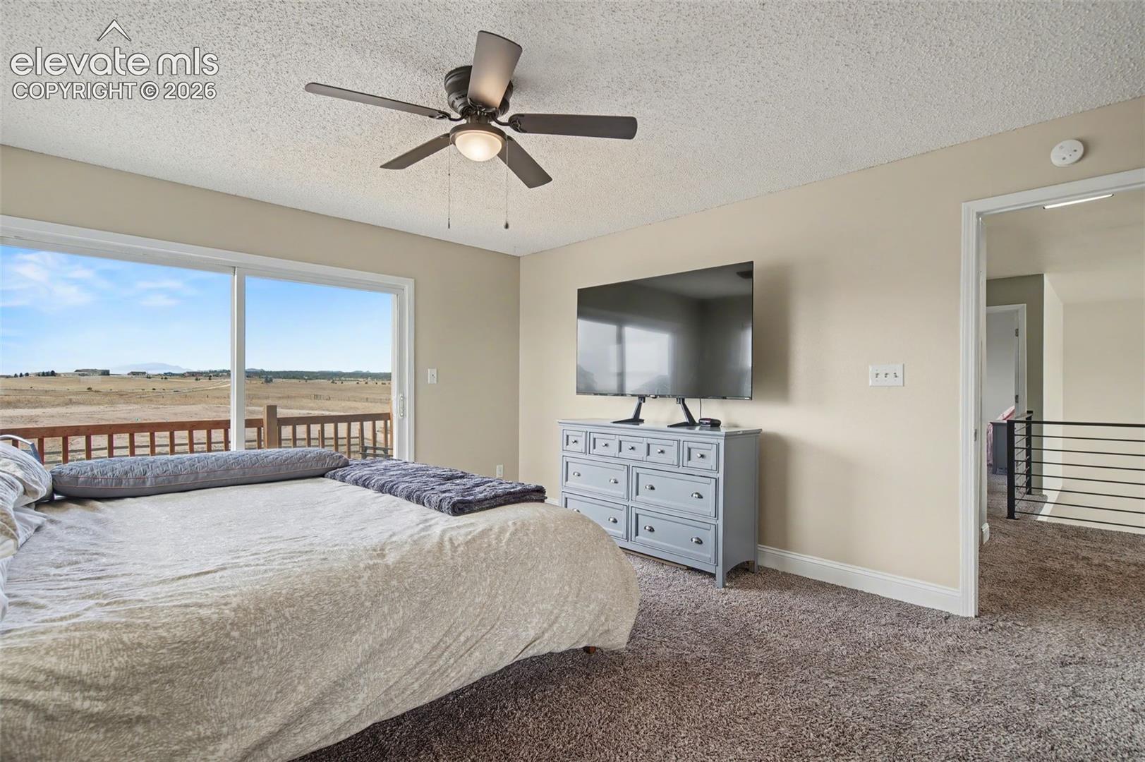 Room featuring large sliding glass doors, a ceiling fan with integrated lighting, wall-to-wall carpeting, and a mountain backdrop