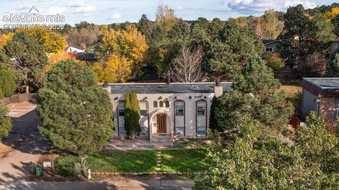 Stucco exterior featuring an arched entryway, stone-accented facade, flat roofline, and paved driveway