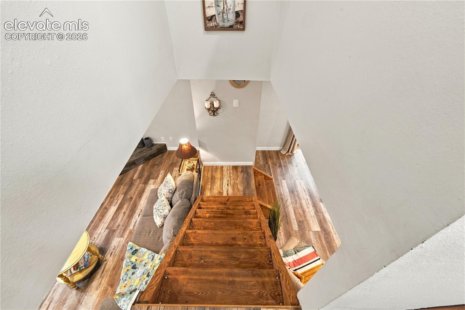 Open floor plan featuring wood-finish flooring, high vaulted ceilings, and custom wood staircase