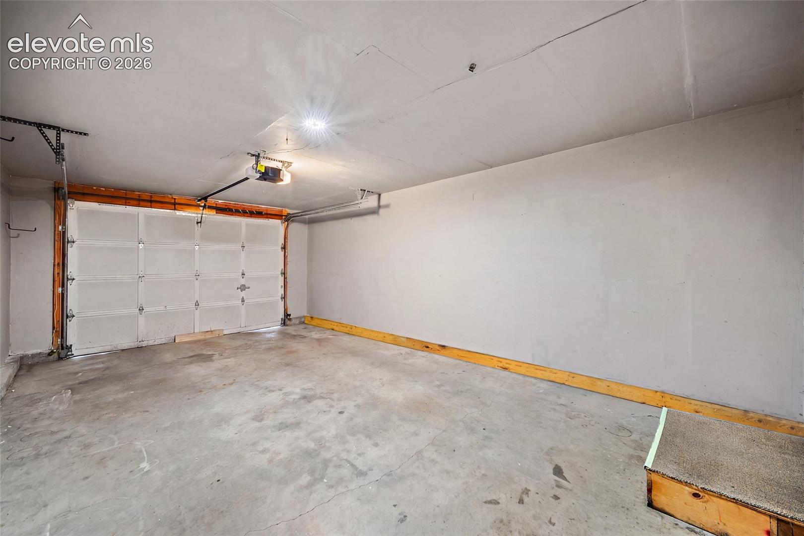 Attached garage with concrete flooring, automatic garage door opener, and overhead lighting