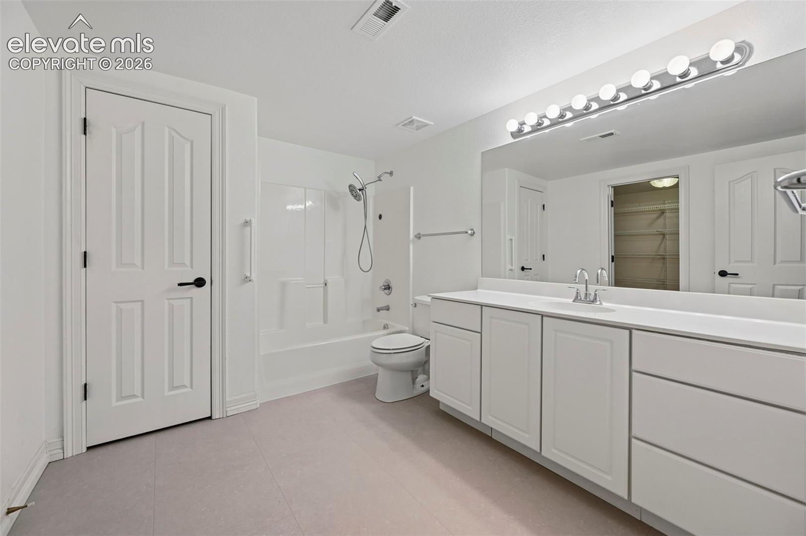 Bathroom featuring a vanity with a white countertop and integrated sink, a large mirror, and an overhead light fixture