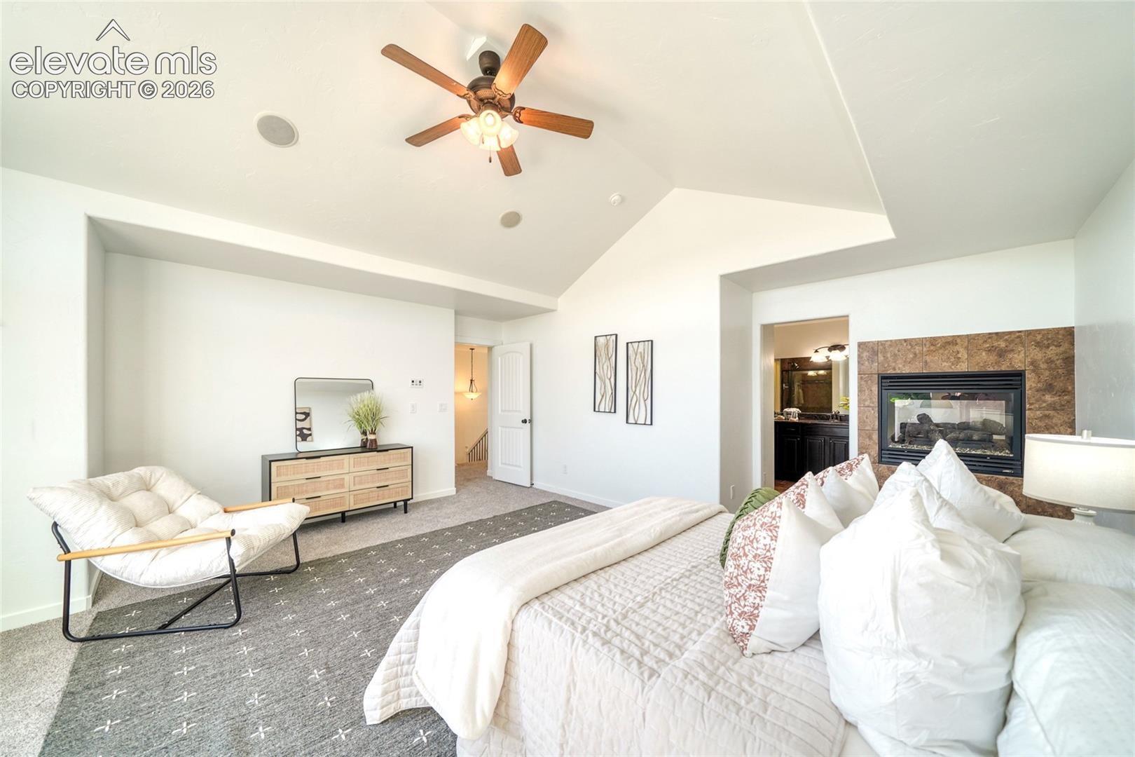 Vaulted ceiling with a ceiling fan, built-in fireplace with stone-finish surround, recessed lighting, and carpet flooring