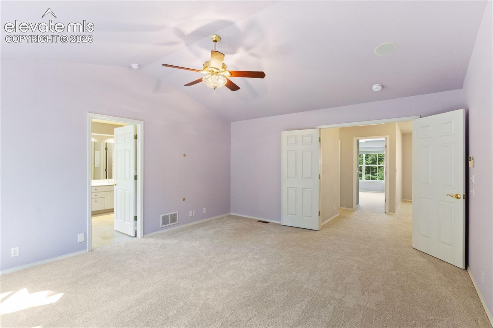 Primary bedroom with vaulted ceiling, french doors, ceiling fan, and ensuite bath