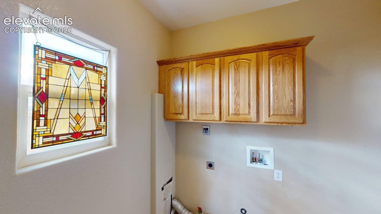 Laundry area featuring wood-finish cabinetry, a framed stained-glass window, and utility hookups