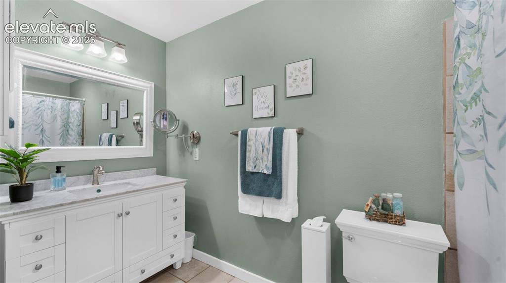 Bathroom featuring a white vanity with an integrated sink, a light-toned countertop, and a framed wall mirror