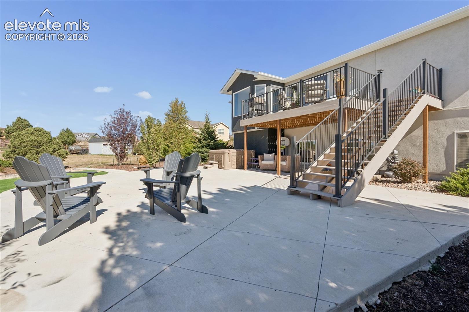 Expansive concrete patio with direct access to a second-story deck, a covered lower-level patio.