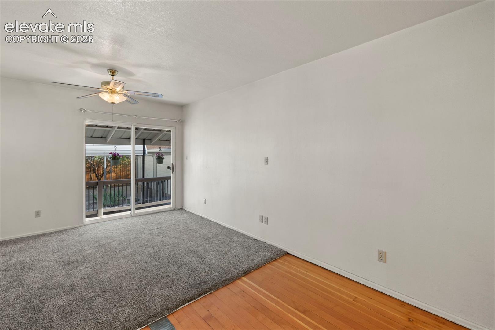Sliding glass door leading to an exterior deck, with a ceiling fan and overhead lighting