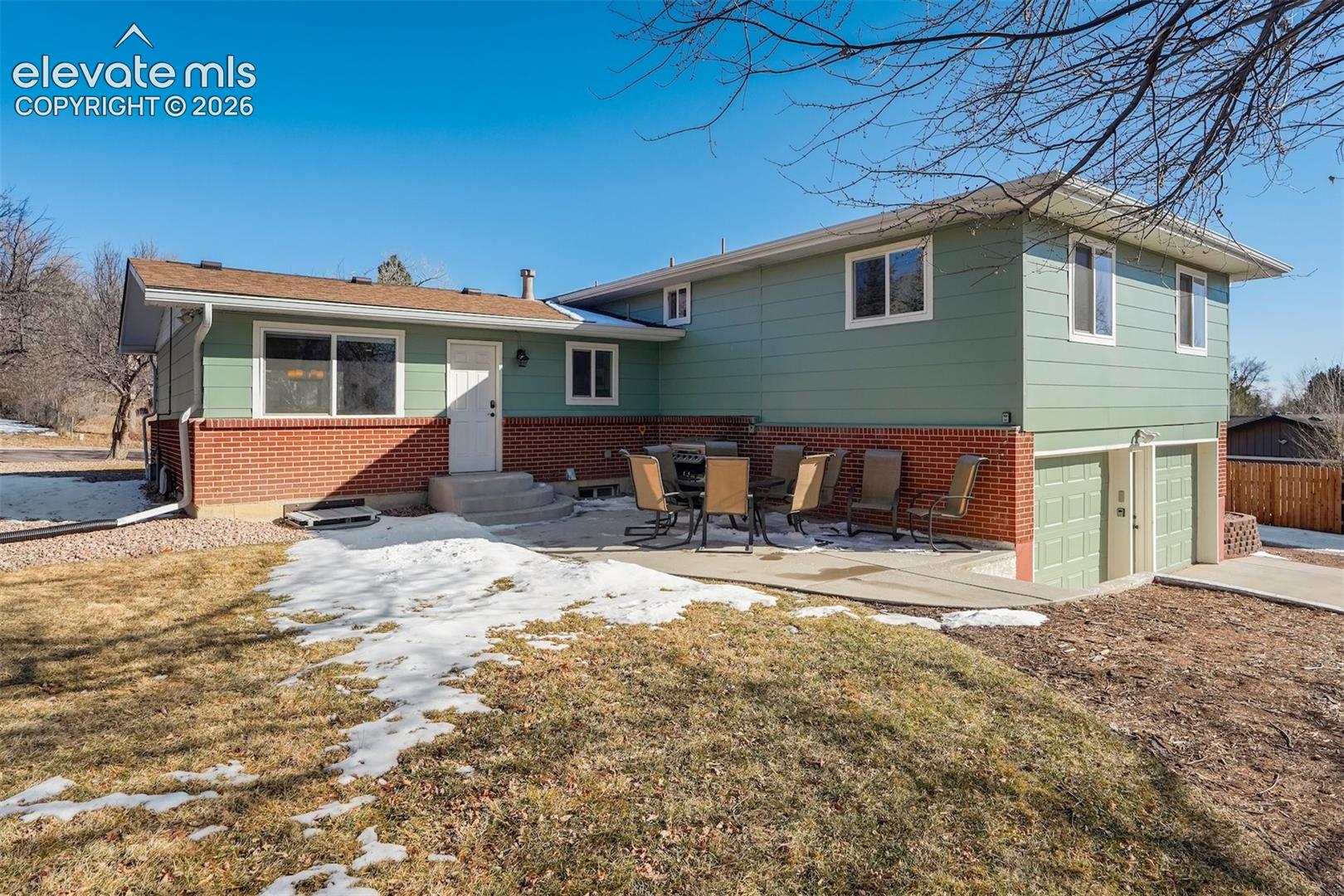 Exterior with green siding, brick accents, concrete patio, and a two-car garage