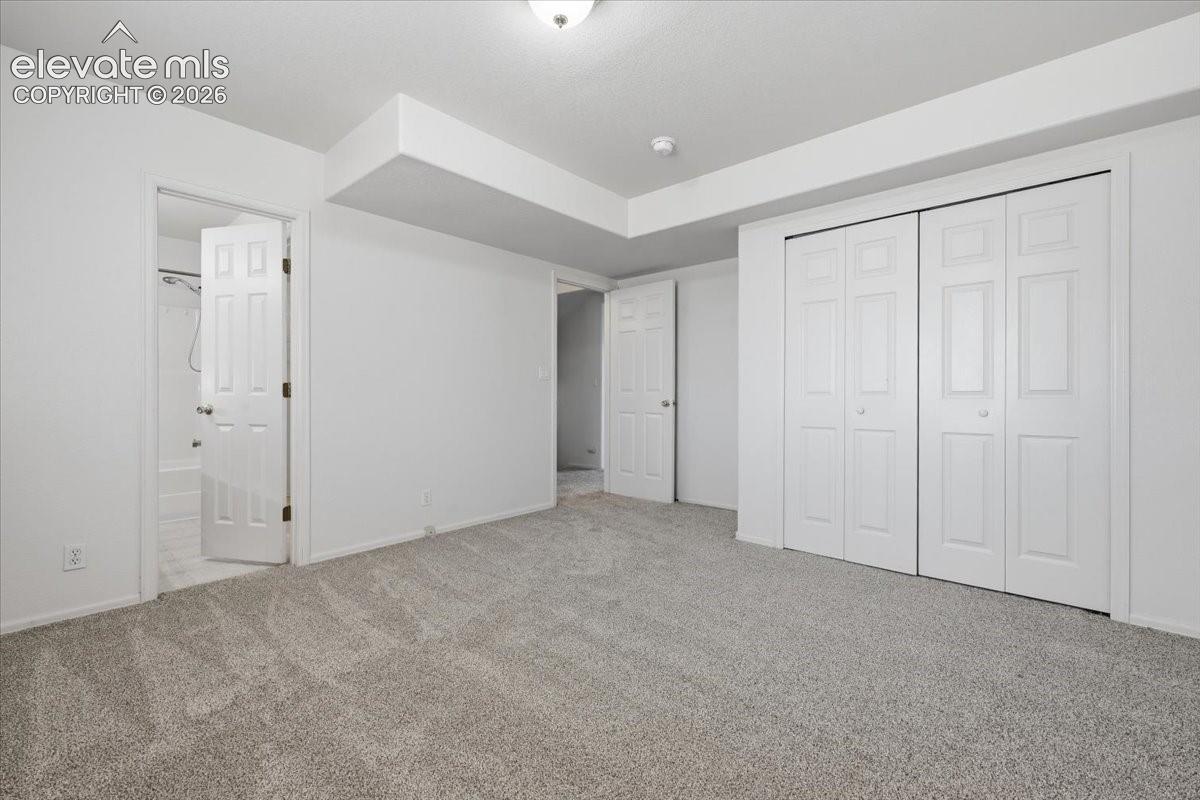 Plush carpeted flooring, bi-fold closet doors, white paneled doors, and ceiling-mounted light fixture