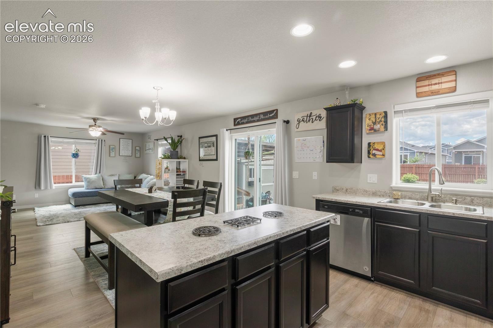 Open-concept living space featuring wood-finish flooring, recessed lighting, and a chandelier