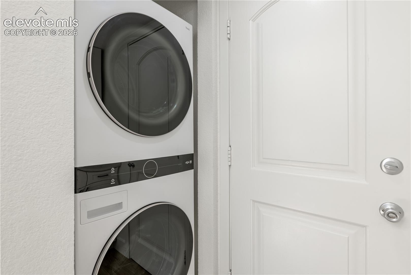 Stacked front-loading washer and dryer unit with a sleek white finish and modern circular door design