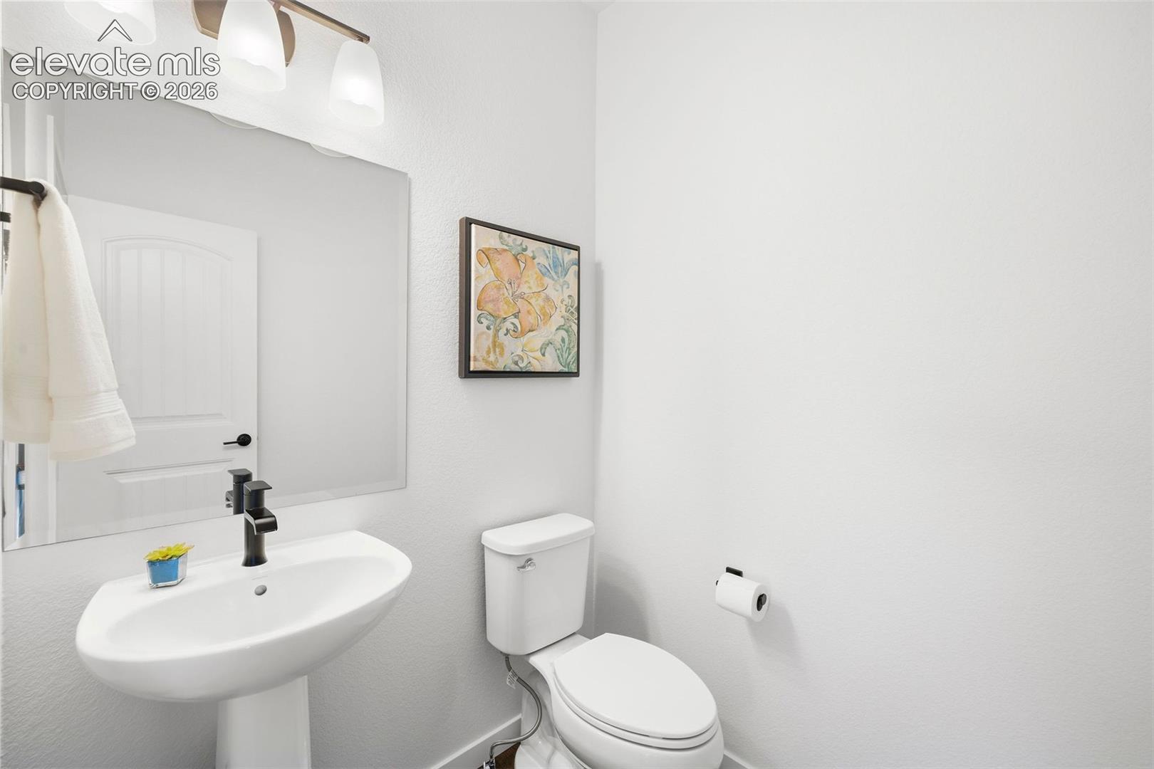 This powder room serves the main level and features a pedestal sing and bronze fixtures. 