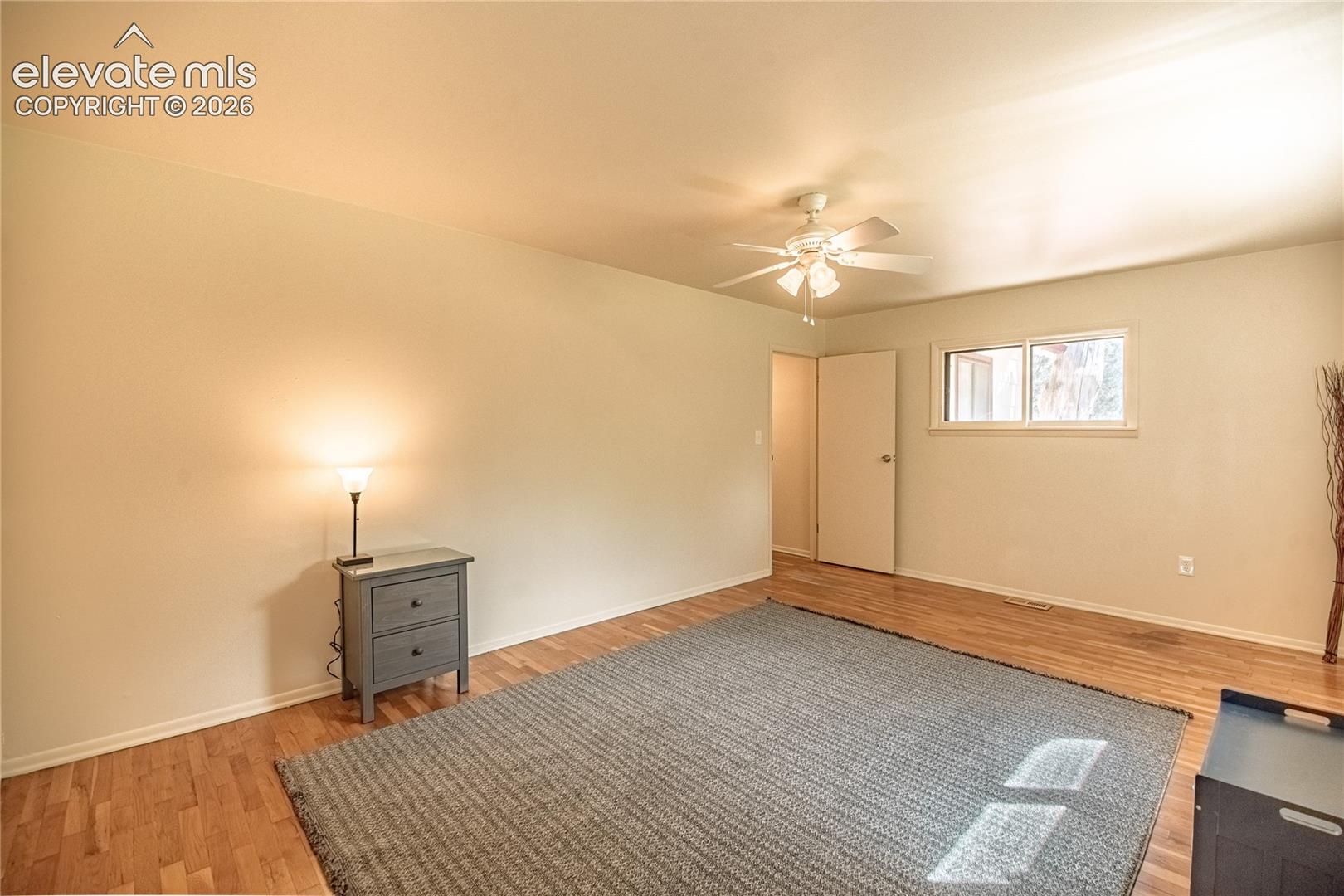 Wood-finish flooring with a ceiling fan light fixture and a double window