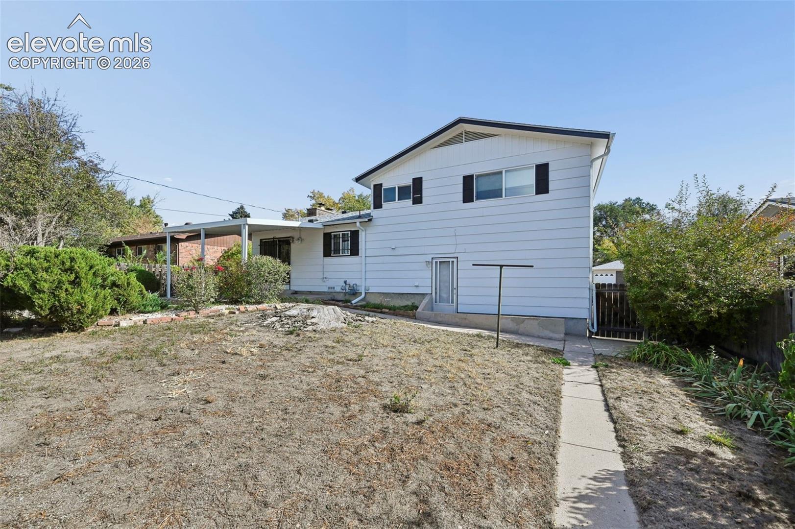 Exterior white siding, covered patio area, concrete walkway, and fenced perimeter