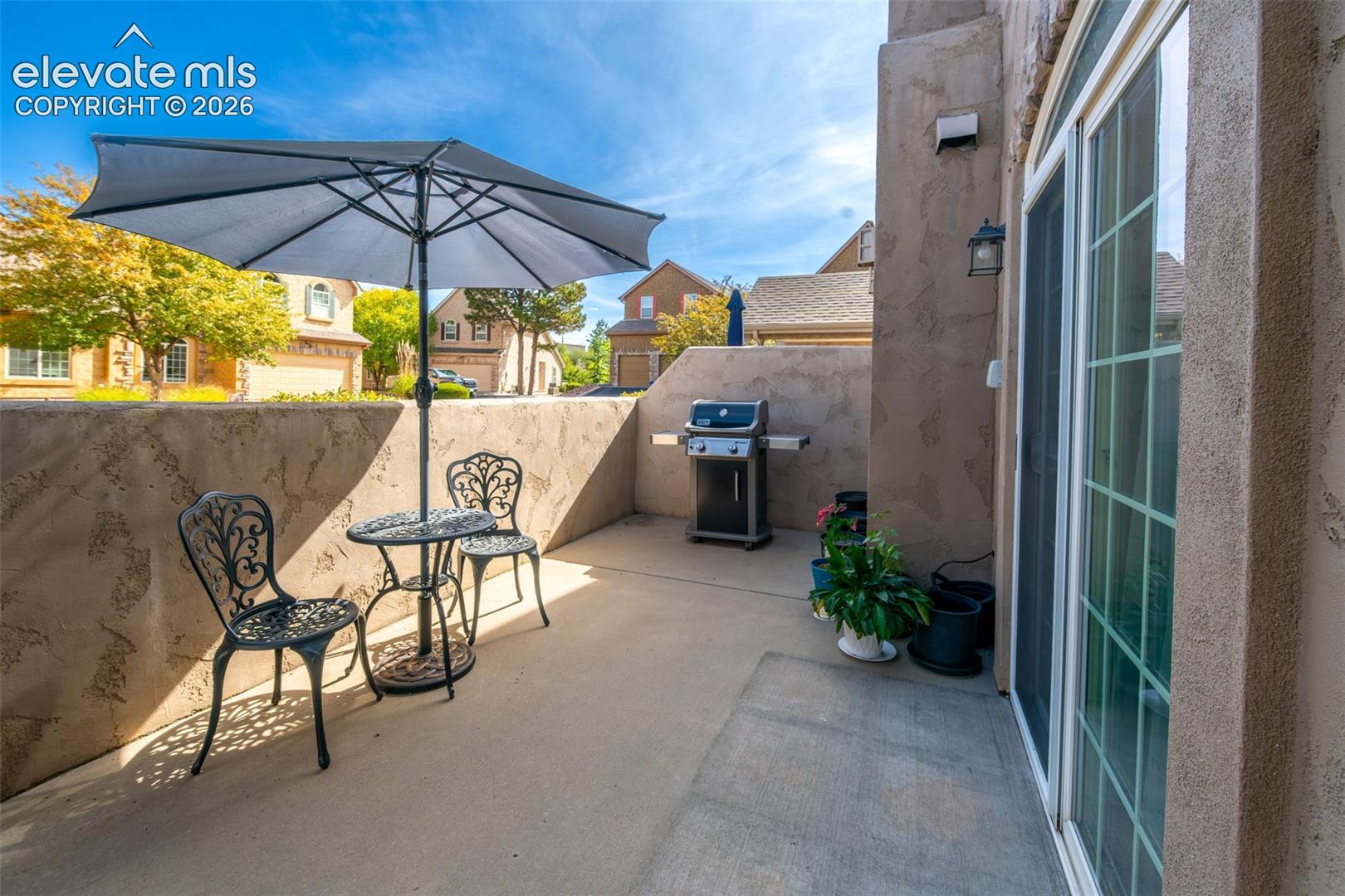 Private patio space featuring stucco walls, concrete flooring, and a sliding glass door