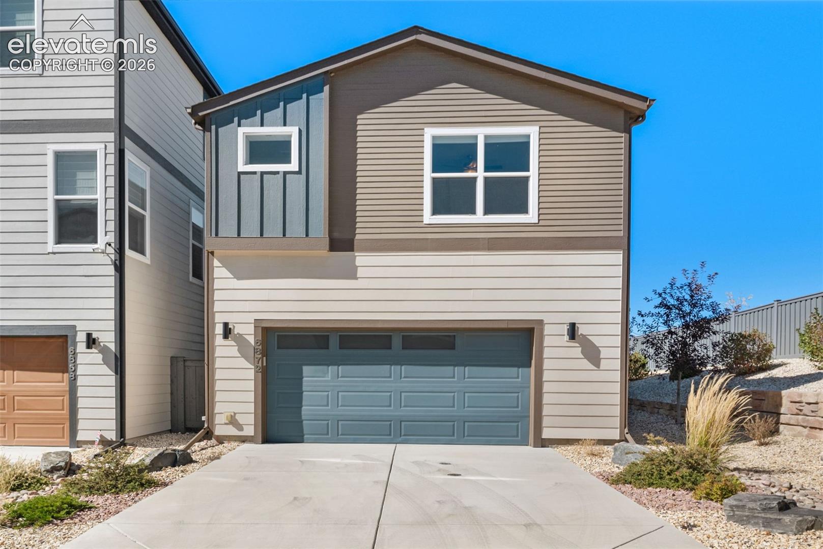 Multi-level exterior featuring horizontal siding, vertical board-and-batten accents, concrete driveway, and attached two-car garage