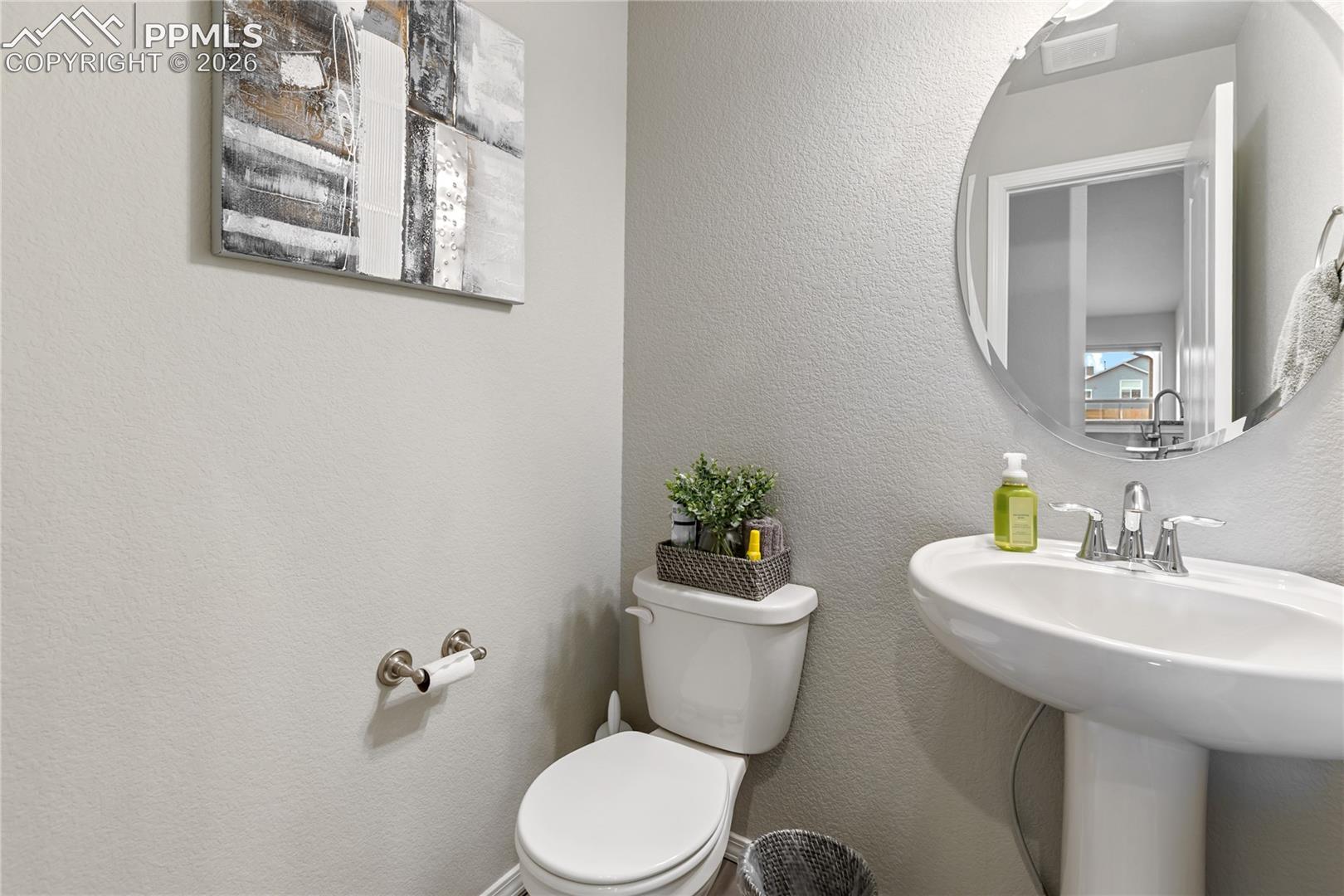 Convenient main-level powder bathroom with pedestal sink and modern finishes.