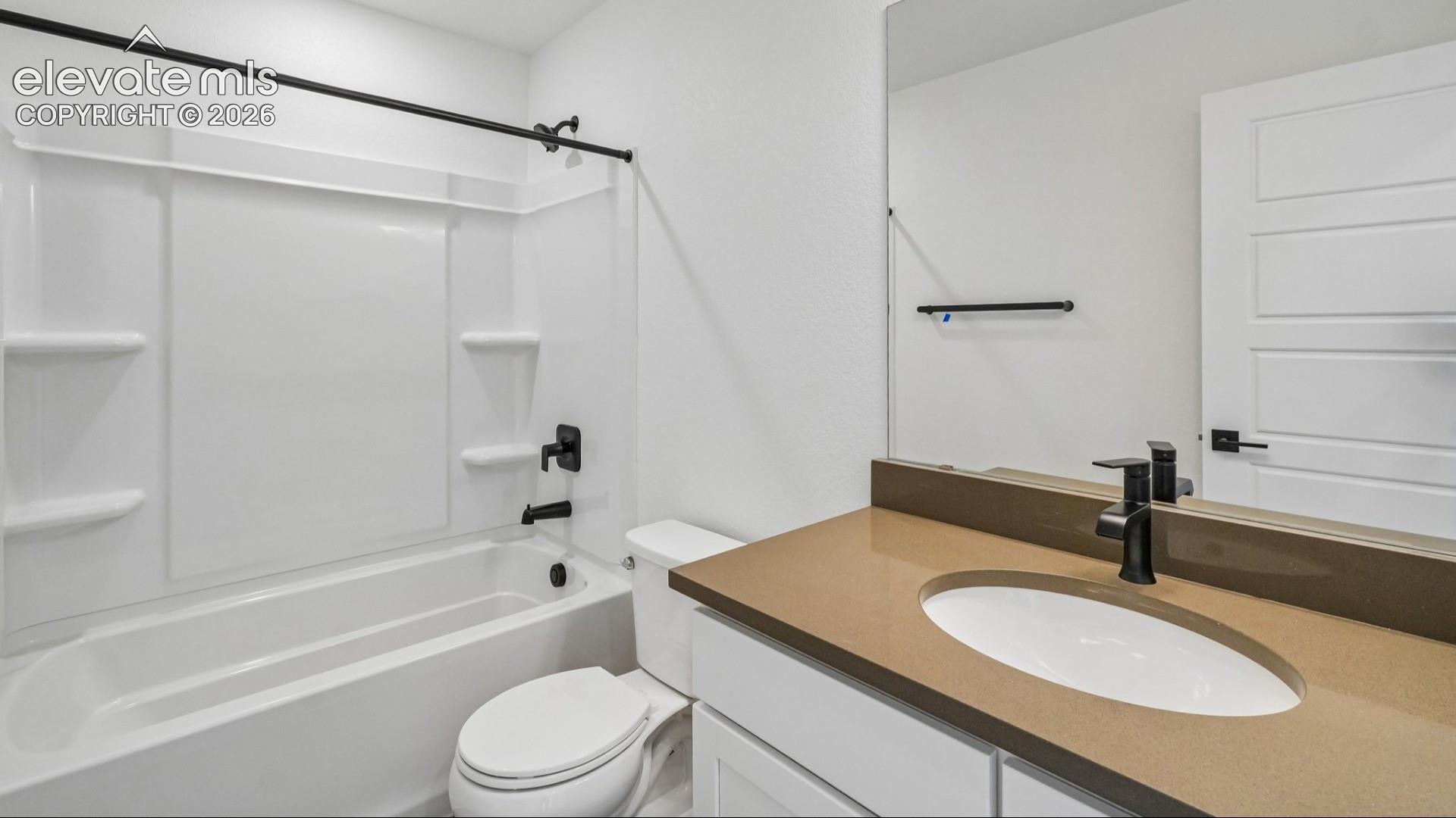 Bathroom featuring a white bathtub and shower surround, solid-surface countertop with an integrated oval sink, matte black fixtures, and a large wall-mounted mirror