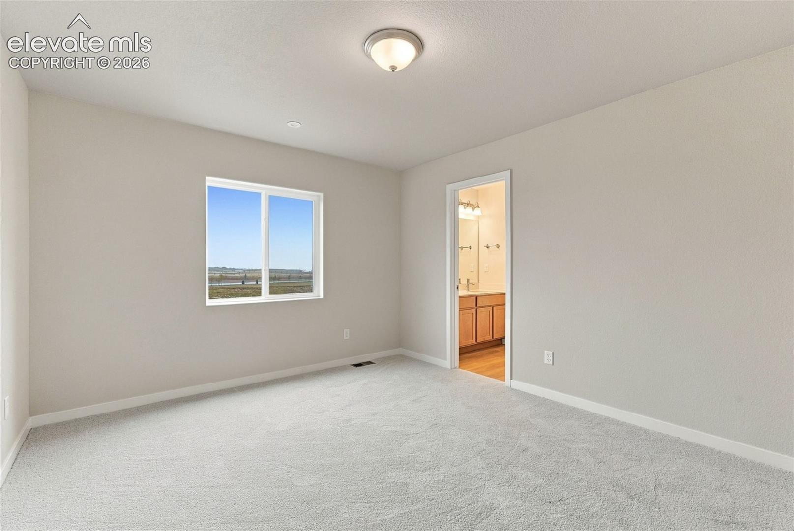 Interior room featuring neutral wall paint, wall-to-wall carpeting, a single window with exterior scenery, and a ceiling-mounted flush light fixture