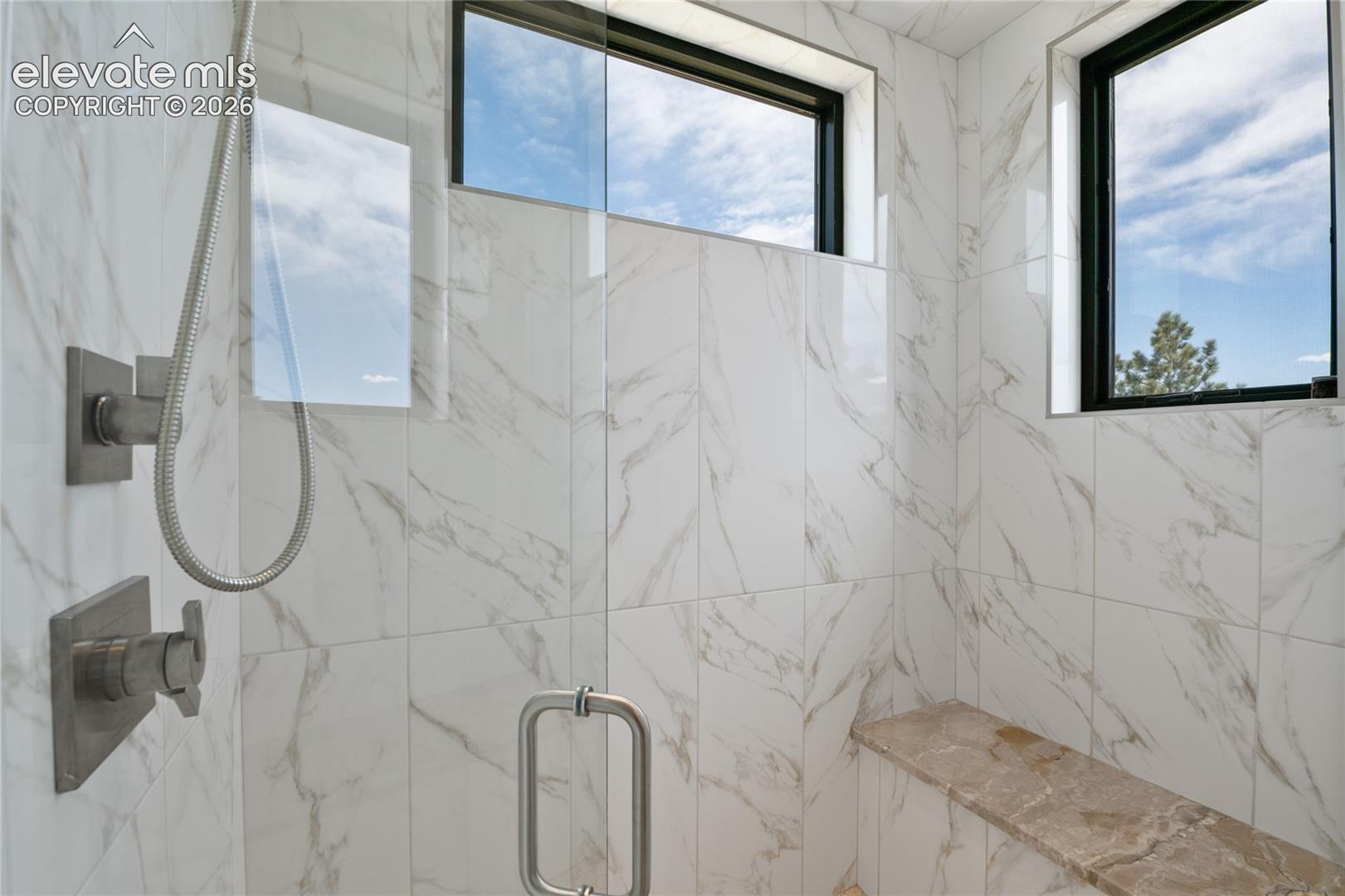 Where every morning starts like a five-star getaway. Full-slab marble steam shower with built-in bench, dual shower systems, and natural light pouring through twin windows.