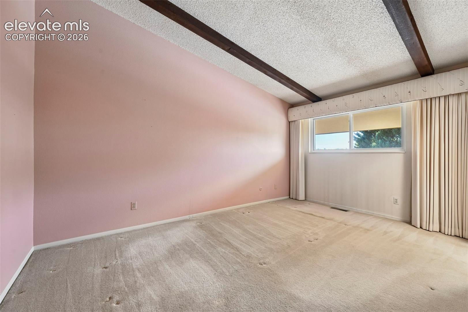 Large primary bedroom with exposed wood beams