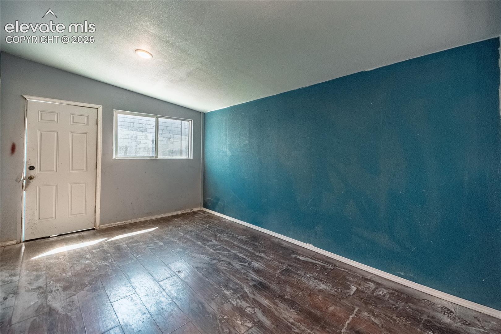 Wood-finish flooring with a multi-pane window, white paneled door, and recessed lighting