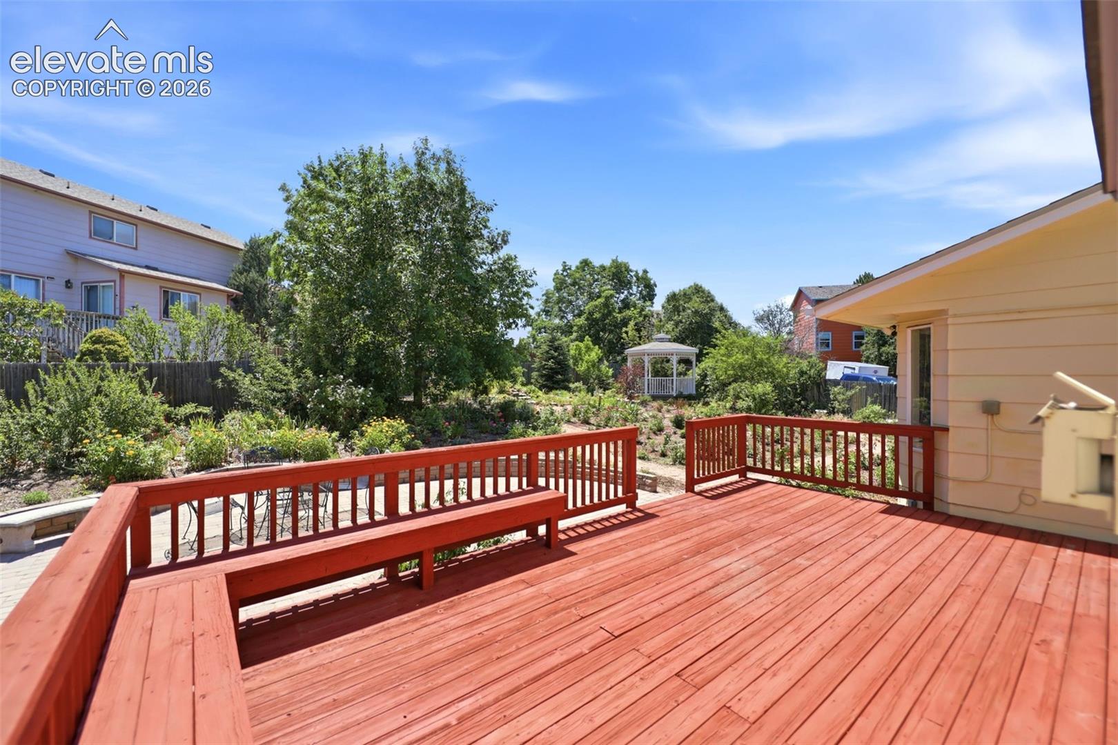Spacious red-stained wood deck featuring integrated bench seating and matching railings