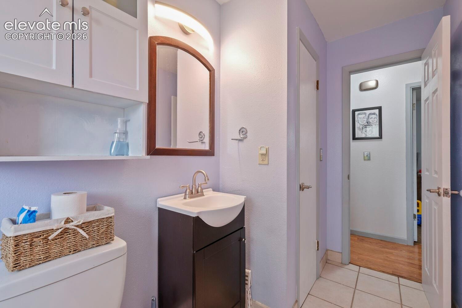 Compact bathroom featuring a dark wood-finish vanity with an integrated sink, brushed nickel faucet, and a wall-mounted mirror