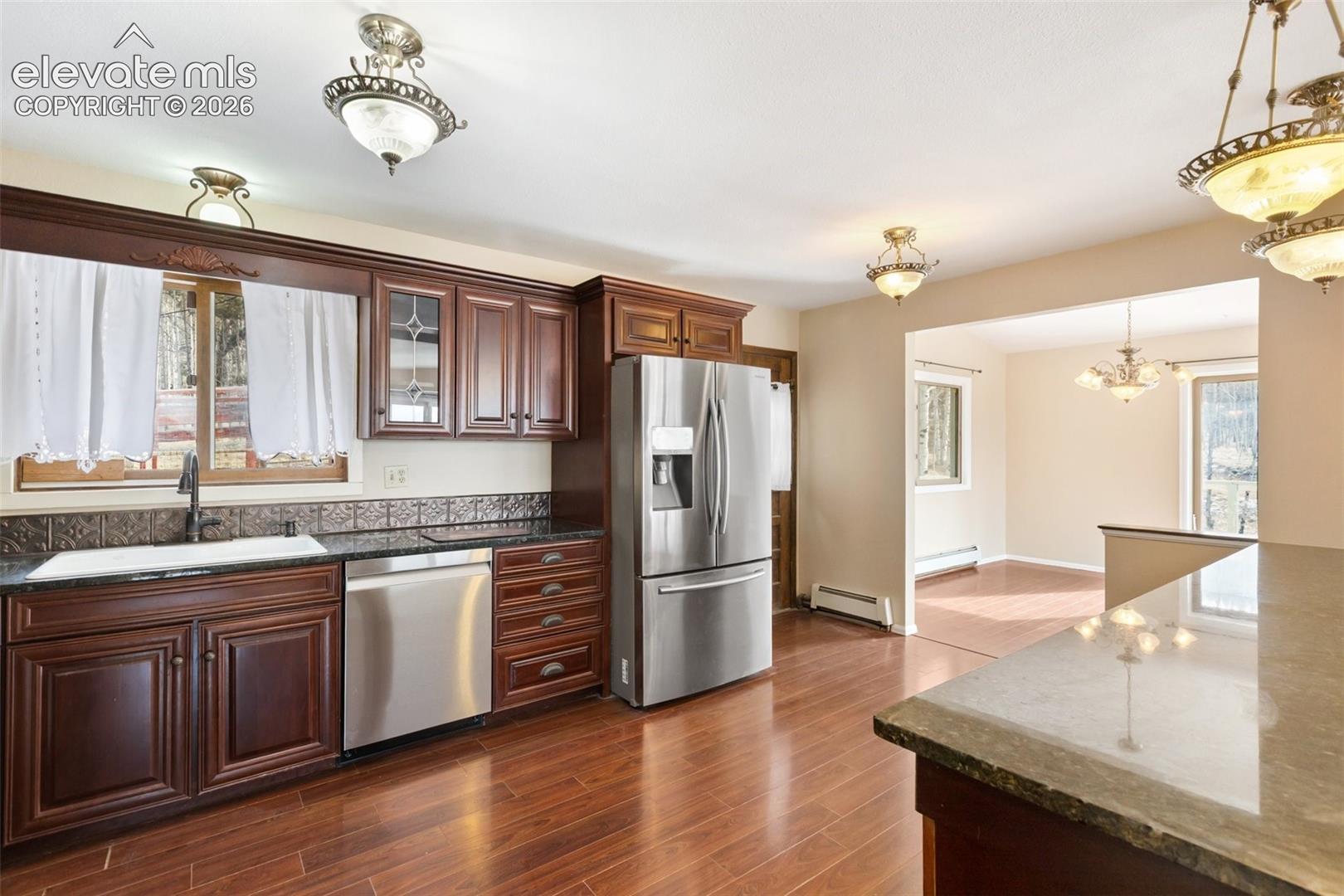 Rich wood-finish flooring, dark wood cabinetry, and stainless steel appliances