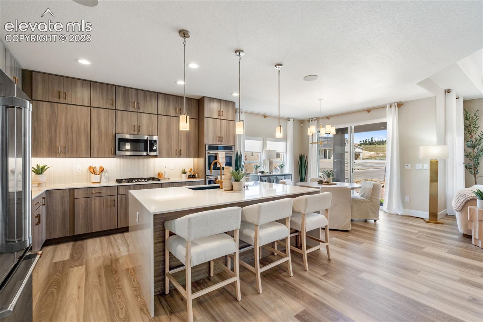 Kitchen featuring flat-panel wood-finish cabinetry, a large central island with quartz countertops, stainless steel built-in appliances, recessed lighting, and wood-finish flooring