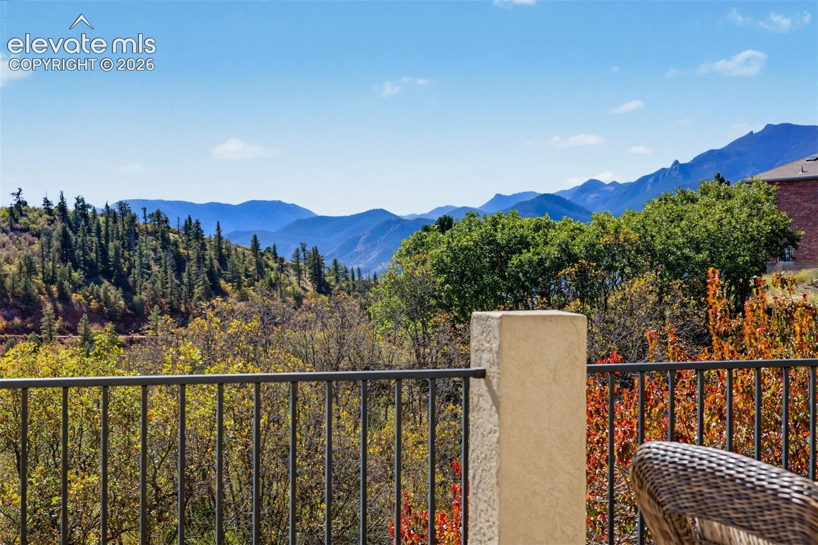 Breathtaking mountain views looking directly out from the back balcony, showcasing the rugged peaks and forested slopes of the Front Range in the Colorado Springs region. The dramatic ridgelines, surrounding foothills, and mature trees create a spectacular natural backdrop for this home in the gated Juniper Ridge at Cedar Heights community.