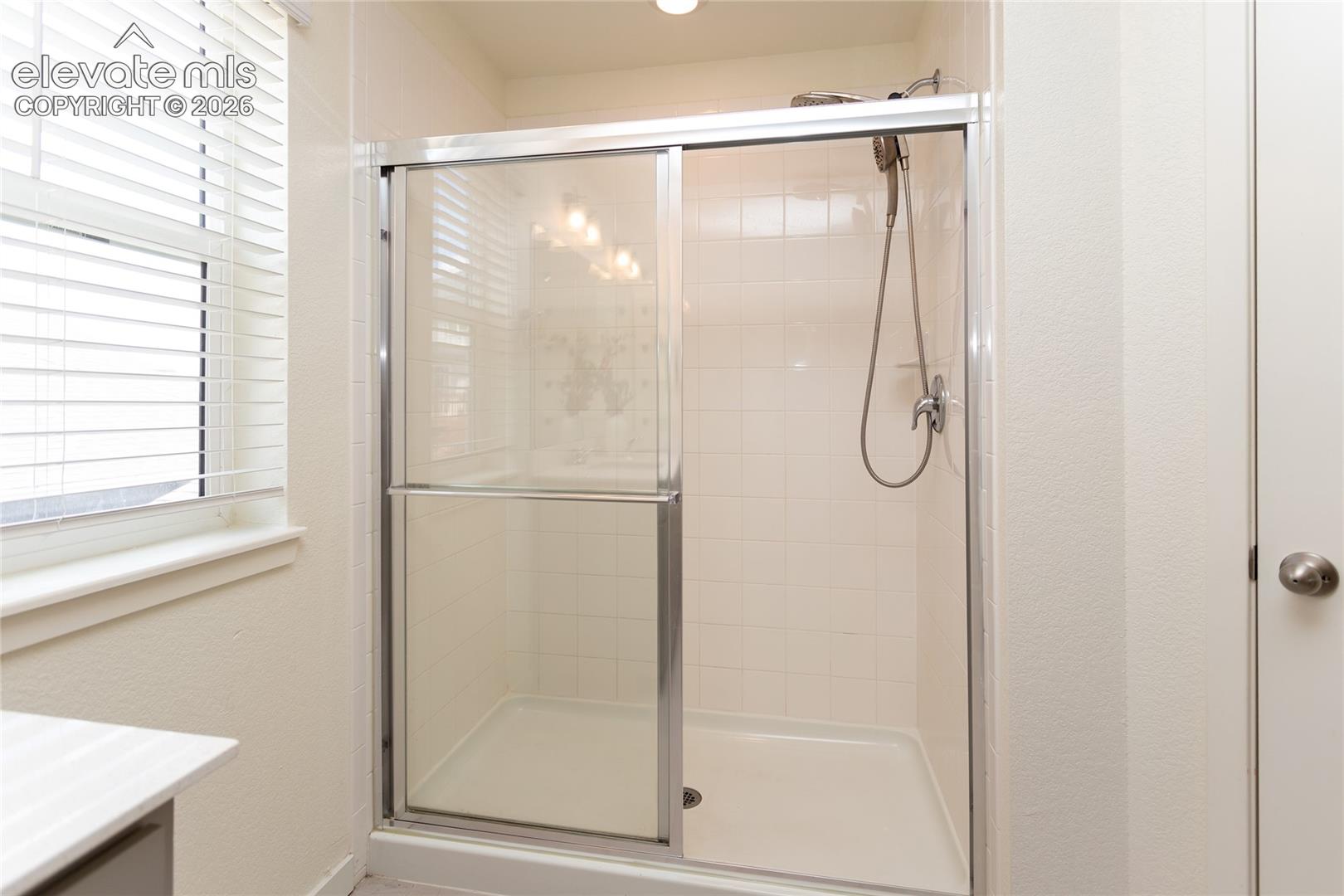 Oversized shower with tile surround and glass doors.
