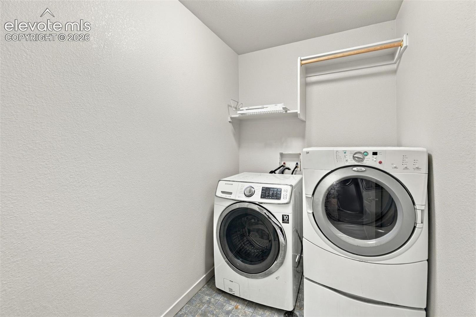 Laundry area featuring neutral wall finishes, overhead storage shelving, and an integrated hanging rod