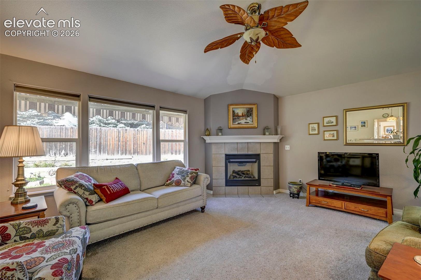 Open plan living: Living room with lofted ceiling, a gas fireplace, and natural light.